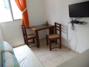 Habitación con escritorio, TV, mesa y sillas. en Apartamento Boa Viagem en Recife