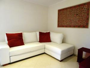 Un sofá blanco con dos almohadas rojas. en Belvilla by OYO Sei Orcia, en Celle sul Rigo