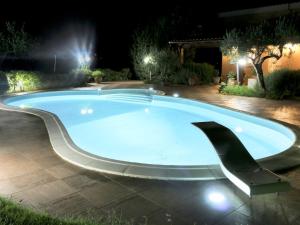 a large swimming pool at night with lights at Belvilla by OYO Villa Rita in Buseto Palizzolo