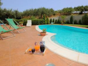 a pool with two glasses of orange juice and two drinks at Belvilla by OYO Villa Rita in Buseto Palizzolo