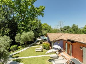 un giardino con sedie e ombrelloni accanto a un edificio di Belvilla by OYO Cozy Holiday Home with barbecue a Polpenazze del Garda