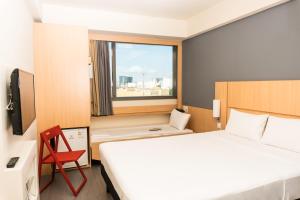 um quarto de hotel com uma cama e uma cadeira vermelha em ibis Rio Porto Atlantico no Rio de Janeiro