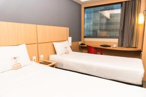 a hotel room with two beds and a desk at ibis Rio Porto Atlantico in Rio de Janeiro