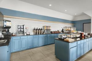a large kitchen with blue cabinets and a counter at Country Inn & Suites by Radisson, Kansas City at Village West, KS in Kansas City