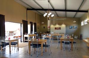 une salle à manger avec des tables et des chaises en bois dans l'établissement Marjaniek Wedding Venue & Guest House, à Rietfontein