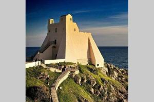 un grande edificio in cima a una collina vicino all'oceano di Blue sky a Sperlonga