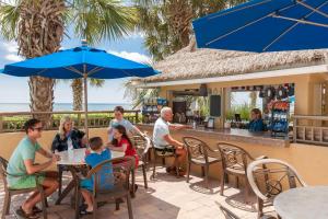 a group of people sitting at a restaurant with blue umbrellas at Holiday Pavilion Resort on the Boardwalk in Myrtle Beach