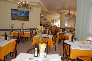 a restaurant with tables and chairs with yellow table cloth at Hotel La Falena in Cervia