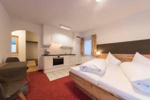 a bedroom with a large bed and a kitchen at Appartements Garni Alpin Live in Samnaun