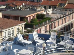 eine Gruppe weißer Stühle und Tische auf einem Balkon in der Unterkunft Hotel Belvedere in Sanremo