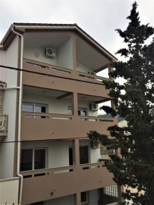 an apartment building with a tree in front of it at Apartments Orhideja in Rab