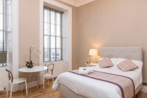 a white bedroom with a bed and a table and chairs at Number 1 Park Apartments in Bristol