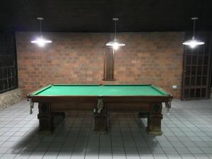 a green pool table in a room with a brick wall at Chacara em Gravata in Gravatá