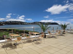 een patio met tafels en stoelen en uitzicht op het water bij Livermead Cliff Hotel in Torquay