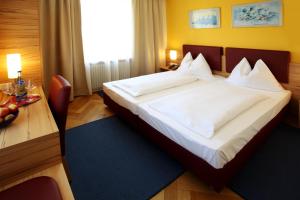 Schlafzimmer mit einem großen weißen Bett und einem Schreibtisch in der Unterkunft Gasthof Rothmayr in Linz