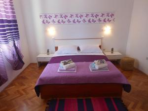 a bedroom with a purple bed with two pillows on it at Donami Apartments in Pag