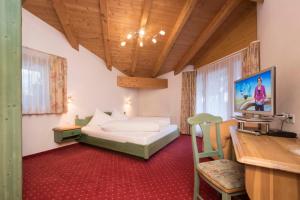 a bedroom with a bed and a desk in a room at Appartements Garni Alpin Live in Samnaun