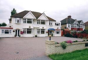 ein großes weißes Haus mit einer Ziegelsteinfahrt in der Unterkunft Nonsuch Park Hotel in Epsom