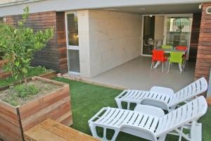 a patio with white benches and a table and chairs at L' Escala Resort in L'Escala