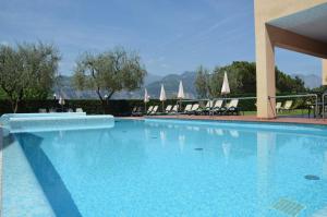 una gran piscina azul con sillas y sombrillas en Residence Lido Hotel, en Malcesine