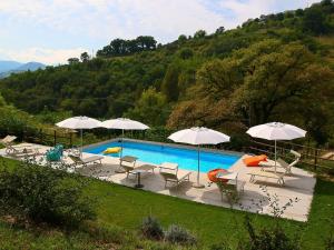 ファブリアーノにあるCozy Villa in Fabriano Italy with Swimming Poolのスイミングプール(椅子、パラソル付)