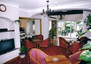 Nonsuch Park Hotel في إبسوم: غرفة طعام بها طاولات وكراسي وتلفزيون