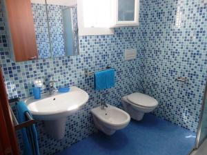 トッレ・サン・ジョヴァンニ・ウジェントにあるVilletta 3 camere Posto Rosso 155 - Verso Sudの青いタイル張りのバスルーム(洗面台、トイレ付)