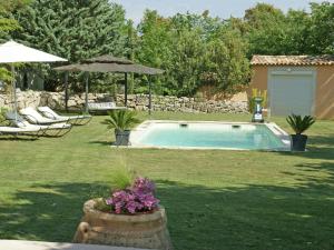 a pool in a yard with chairs and an umbrella at Detached villa with enclosed beautiful garden and private pool 1km from C reste in Reillanne