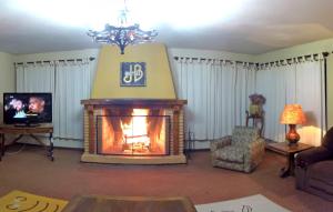 a living room with a fireplace and a tv at Hotel JB in Campos do Jordão