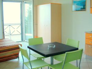 ヴェルバーニアにあるApartment in a residence on Lake Maggiore near the beachのダイニングルーム(黒いテーブル、緑の椅子付)