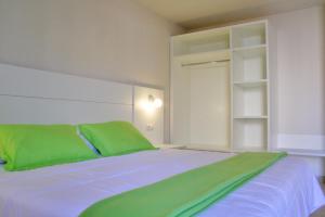a bedroom with a bed with green pillows at L' Escala Resort in L'Escala