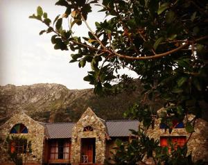 una casa de piedra con una montaña en el fondo en El hostel secreto en Lago Puelo