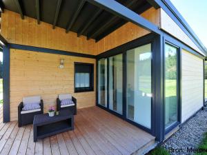 a screened porch with two chairs on a wooden deck at Comfortable apartment with balcony in Abreschviller