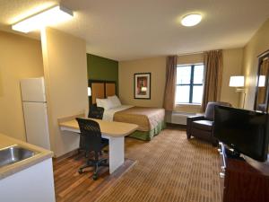 a hotel room with a bed and a desk and a television at Extended Stay America Suites - Toledo - Holland in Holland