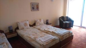 a small bedroom with a bed and a chair at Guest House Pri Valyo in Primorsko