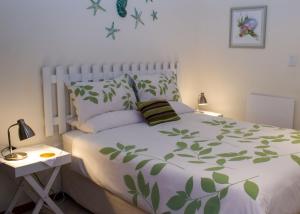 a bedroom with a white bed with green leaves on it at Haus Giotto in Gansbaai