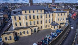 ein großes gelbes Gebäude mit Autos auf einem Parkplatz in der Unterkunft Maldron Hotel Shandon Cork City in Cork