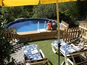 2 personnes assises sous un parasol à côté d'une piscine dans l'établissement Pretty chalet in Beaulieu with private pool, à Beaulieu