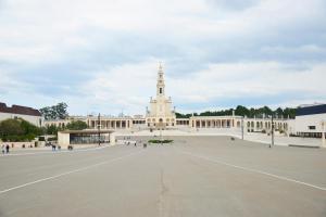 a large white building with a church in the background at Parque dos Pastores in Fátima