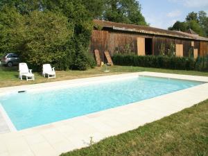 a swimming pool with two chairs and a house at Superb villa with private heated pool in Revigny-sur-Ornain