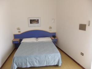 ein Schlafzimmer mit einem blauen Bett in einem weißen Zimmer in der Unterkunft Hotel La Falena in Cervia