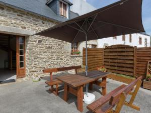 mesa de picnic con sombrilla y 2 bancos en Holiday home with enclosed garden, en Pont-Croix