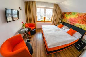 een slaapkamer met een bed en 2 oranje stoelen bij Penzion Panda in Turčianske Teplice