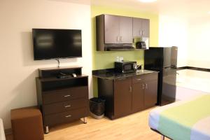 a hotel room with a television and a kitchen with a bed at Studio 6 Victorville - Apple Valley in Victorville