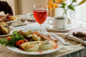 uma mesa com um prato de comida e um copo de vinho em Berry Manor Inn em Rockland