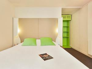 Una cama con almohadas verdes y un libro. en Campanile Aix-Les-Bains, en Aix-les-Bains