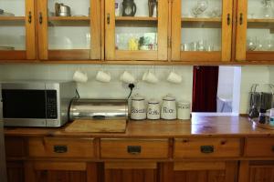 a kitchen counter with a microwave and some cups at Woodcroft in Lidgetton