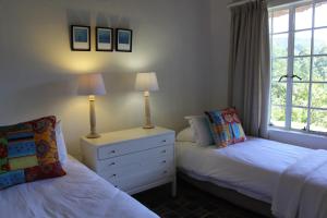 a bedroom with two beds and a dresser and a window at Woodcroft in Lidgetton