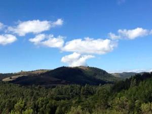 a view of a mountain with trees and clouds at Pousada Chalés da Lua in Munhoz