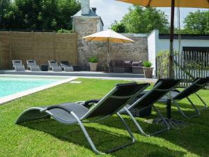 eine Gruppe von Gartenstühlen und einem Sonnenschirm neben einem Pool in der Unterkunft Modern Mansion in Hasti re par Del with Pool in Hastière-par-delà